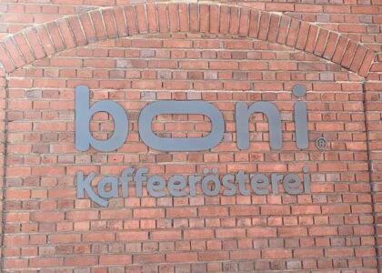 Rote Klinkerwand aus Backstein mit grauem Schriftzug in der Mitte: boni. Kaffeerösterei.