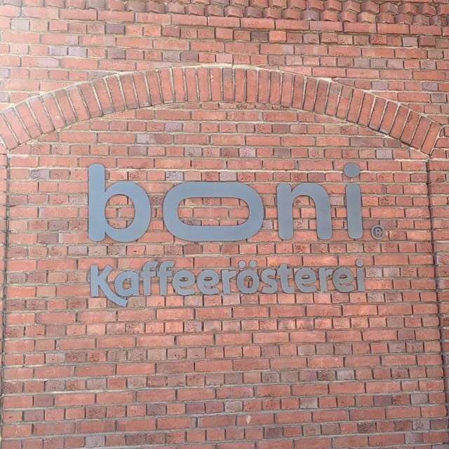 Rote Klinkerwand aus Backstein mit grauem Schriftzug in der Mitte: boni. Kaffeerösterei.