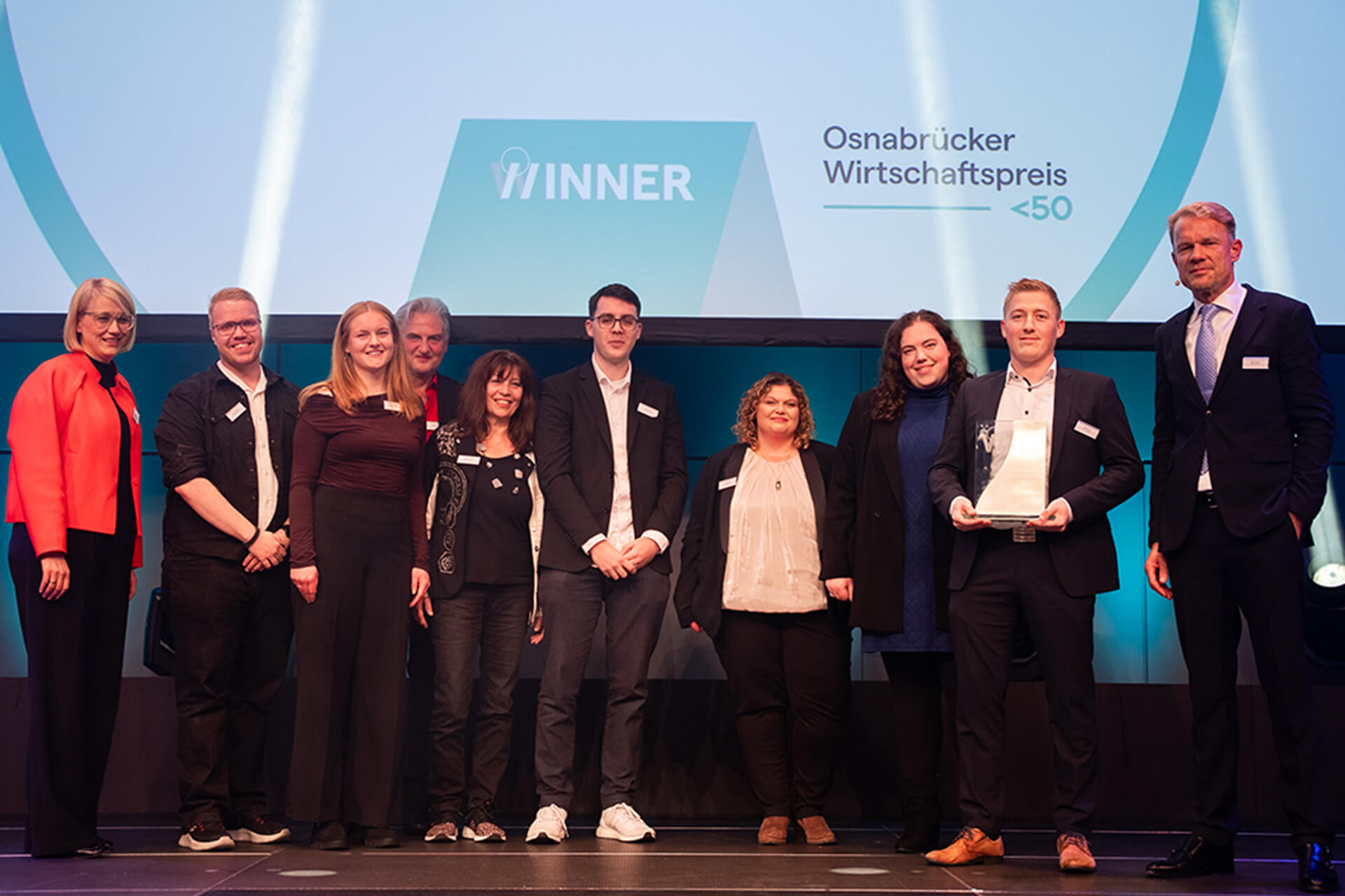 Eine Gruppe von Personen steht bei einer Preisverleihung auf der Bühne und hält den Osnabrücker Wirtschaftspreis.