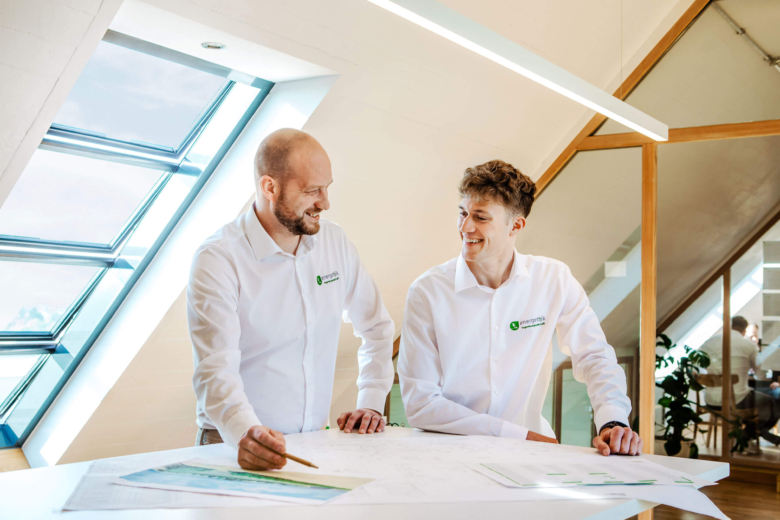 2 energethik Mitarbeiter stehend an einem Tisch mit Unterlagen