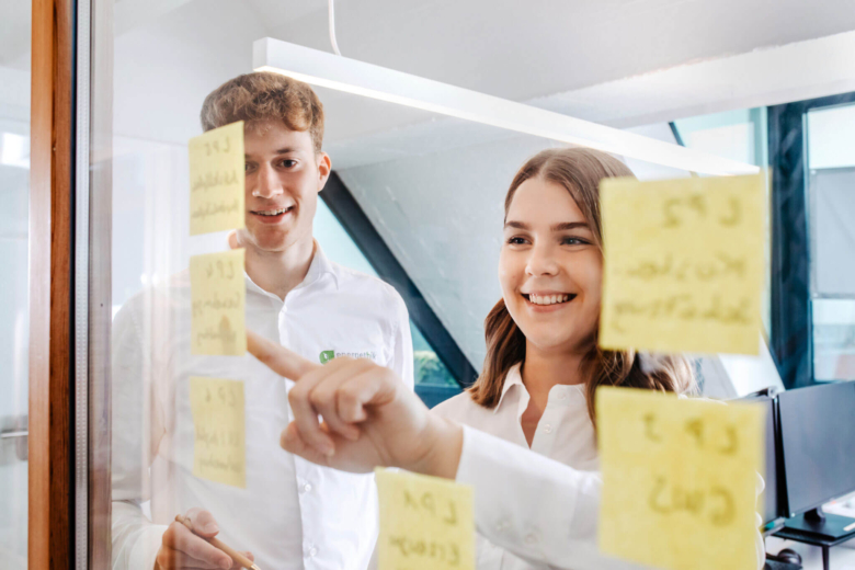 2 Mitarbeiter von energethik stehen vor einer Scheibe mit Post-Its