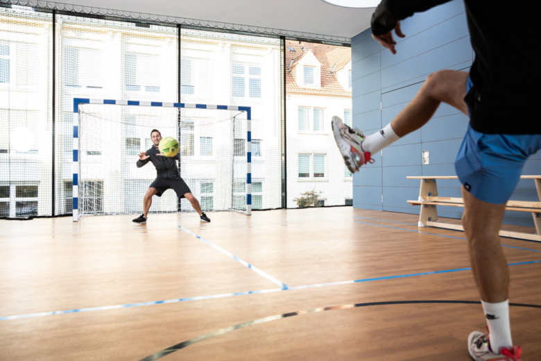 Zwei Personen in einem Sportraum spielen Fußball