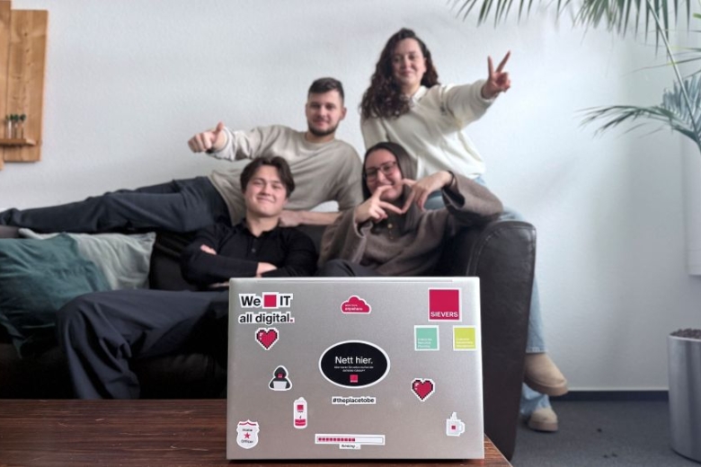 Vier Mitarbeiter der SIVERS GROUP auf einem Sofa im Hintergrund. Im Vordergrund steht ein LapTop mit diversn Stickern.