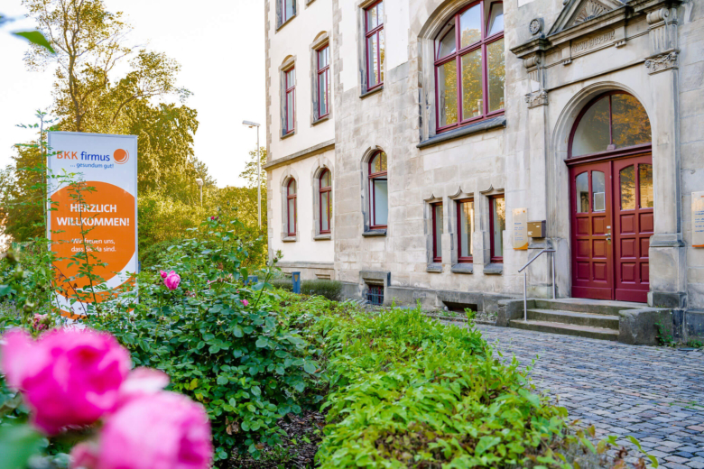 Der Haupteingang der BKK firmus Geschäftsstelle mit barrierefreier Rampe und Willkommensschild.
