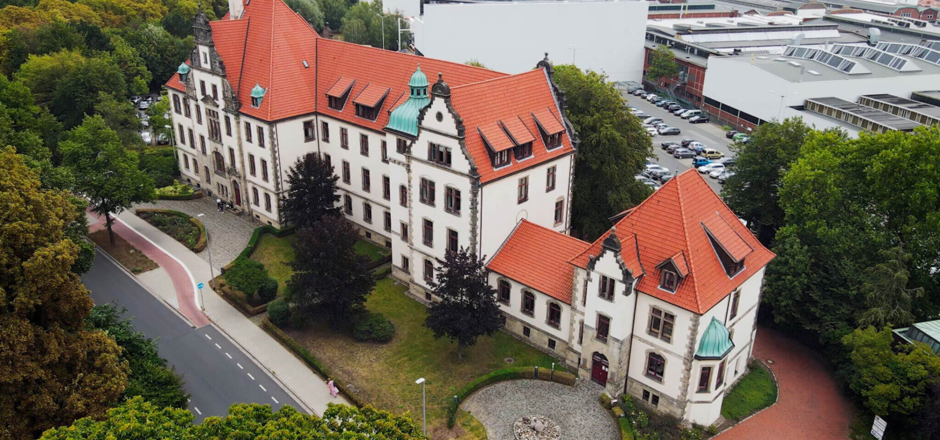 Luftaufnahme des historischen Hauptgebäudes der BKK firmus in einer grünen Umgebung.