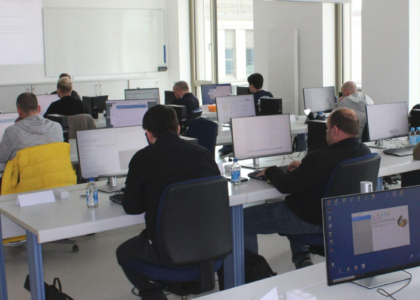Teilnehmende eines IT- oder Cybersecurity-Schulungsprogramms an ihren Computern im Seminarraum.