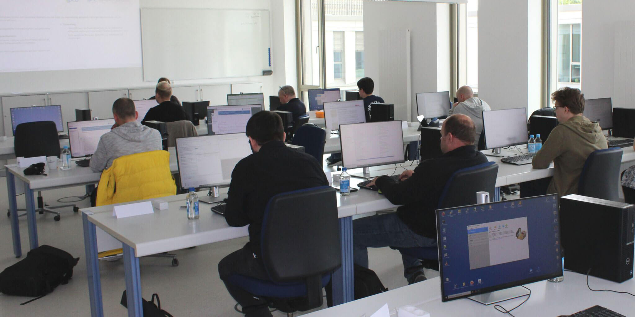Teilnehmende eines IT- oder Cybersecurity-Schulungsprogramms an ihren Computern im Seminarraum.