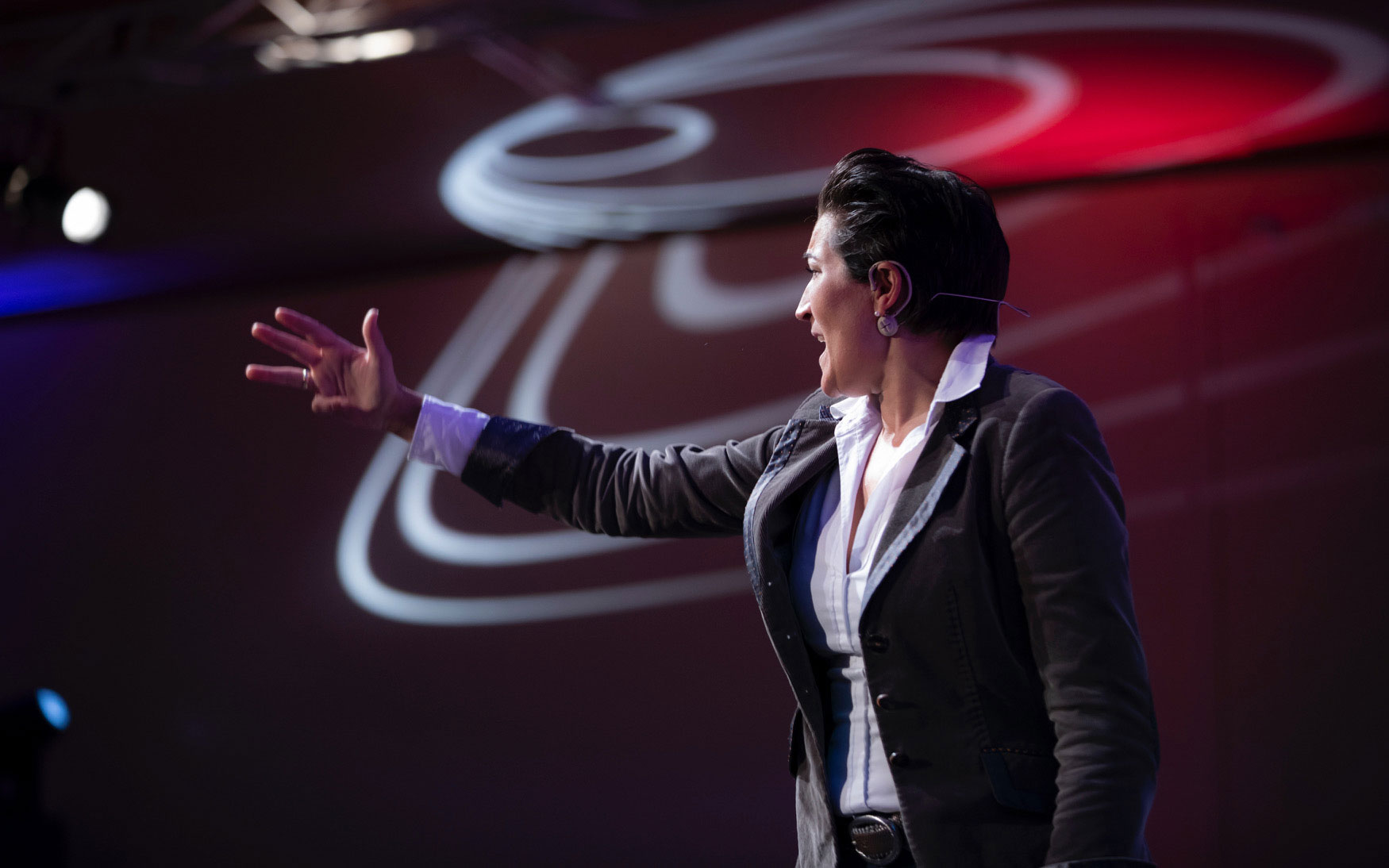 Daniela A. Ben Said im Blazer gestikuliert dynamisch mit der Hand während eines Vortrags auf einer ausgeleuchteten Bühne.