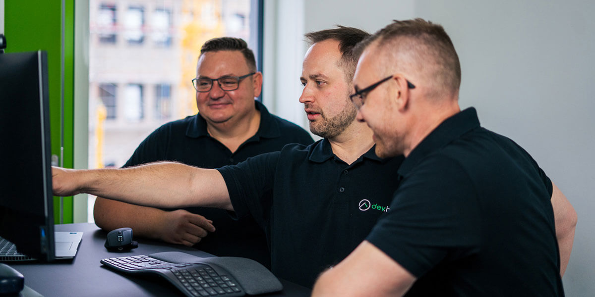 Drei Softwareentwickler von dev.house bei der gemeinsamen Code-Review am Bildschirm.