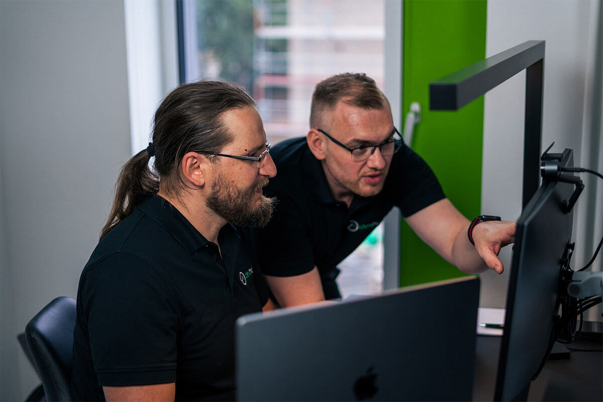 Entwickler-Team bei der gemeinsamen Problemlösung am Bildschirm.