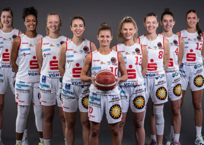 Mannschaftsfoto der Girolive-Panthers Osnabrück: Neun Basketballspielerinnen stehen lächelnd in ihren weiß-roten Trikots nebeneinander; die Spielerin in der Mitte hält einen Basketball.