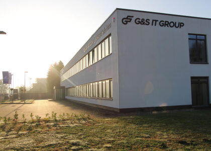 Modernes, weißes Firmengebäude der G&S IT GROUP bei tief stehender Sonne im Gegenlicht.