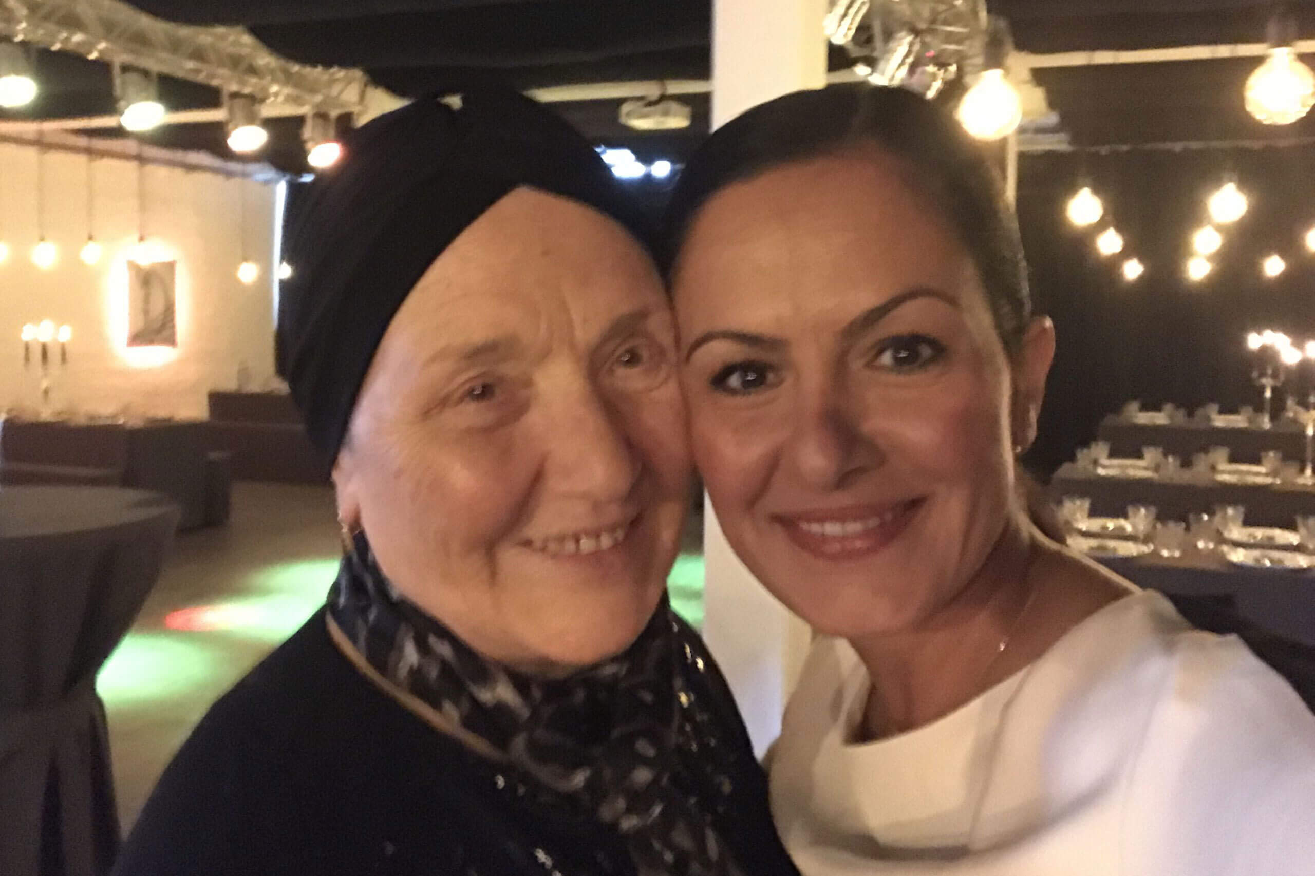Nahaufnahme von Frau H. Nezir, die gemeinsam mit einer älteren Frau lächelnd in einem festlich beleuchteten Veranstaltungsraum posiert.