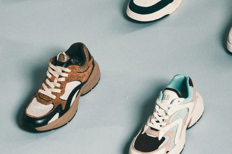 Verschiedene Sneaker in unterschiedlichen Farben und Designs auf hellgrauem Hintergrund von oben fotografiert