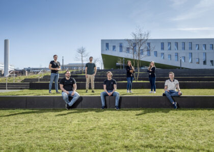 Sieben junge Menschen verteilen sich sitzend und stehend auf den begrünten Terrassenstufen Osnabrücker Hochschulcampus.