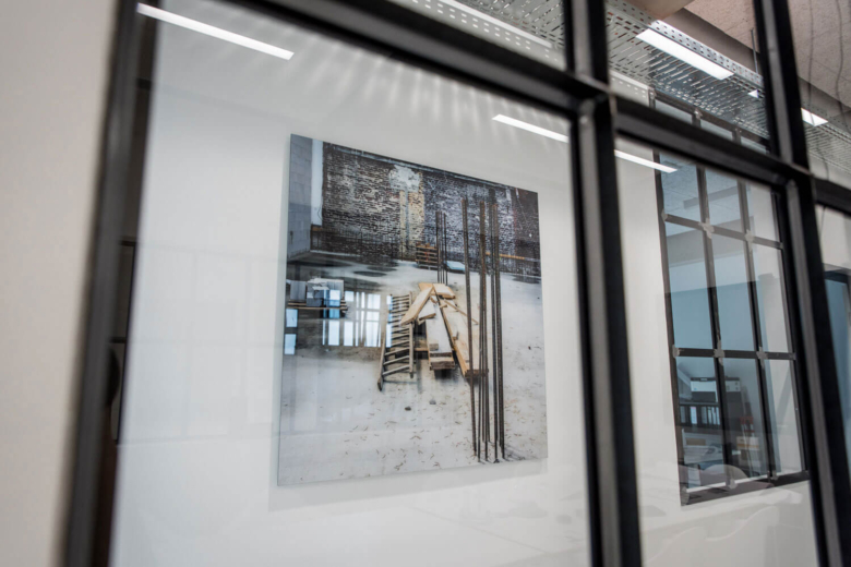 Großformatiges Wandbild einer Baustelle, gesehen durch eine moderne Glas-Trennwand.