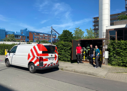 Drei Personen stehen neben einem SWO-Einsatzfahrzeug vor einer geöffneten Gas-Messstation im Freien.