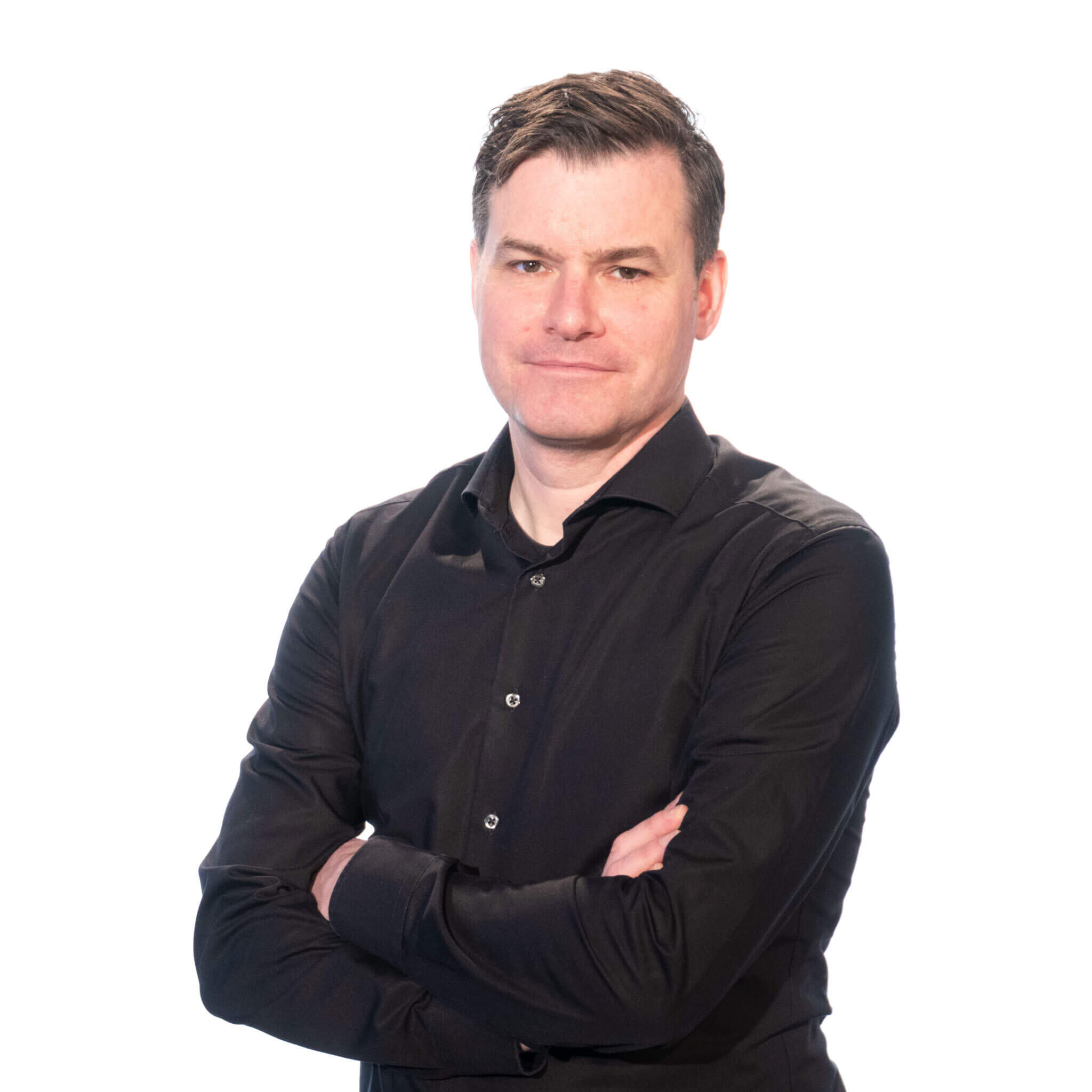 Jan Jansen vor weißem Hintergrund mit verschränkten Armen in einem schwarzen Hemd.