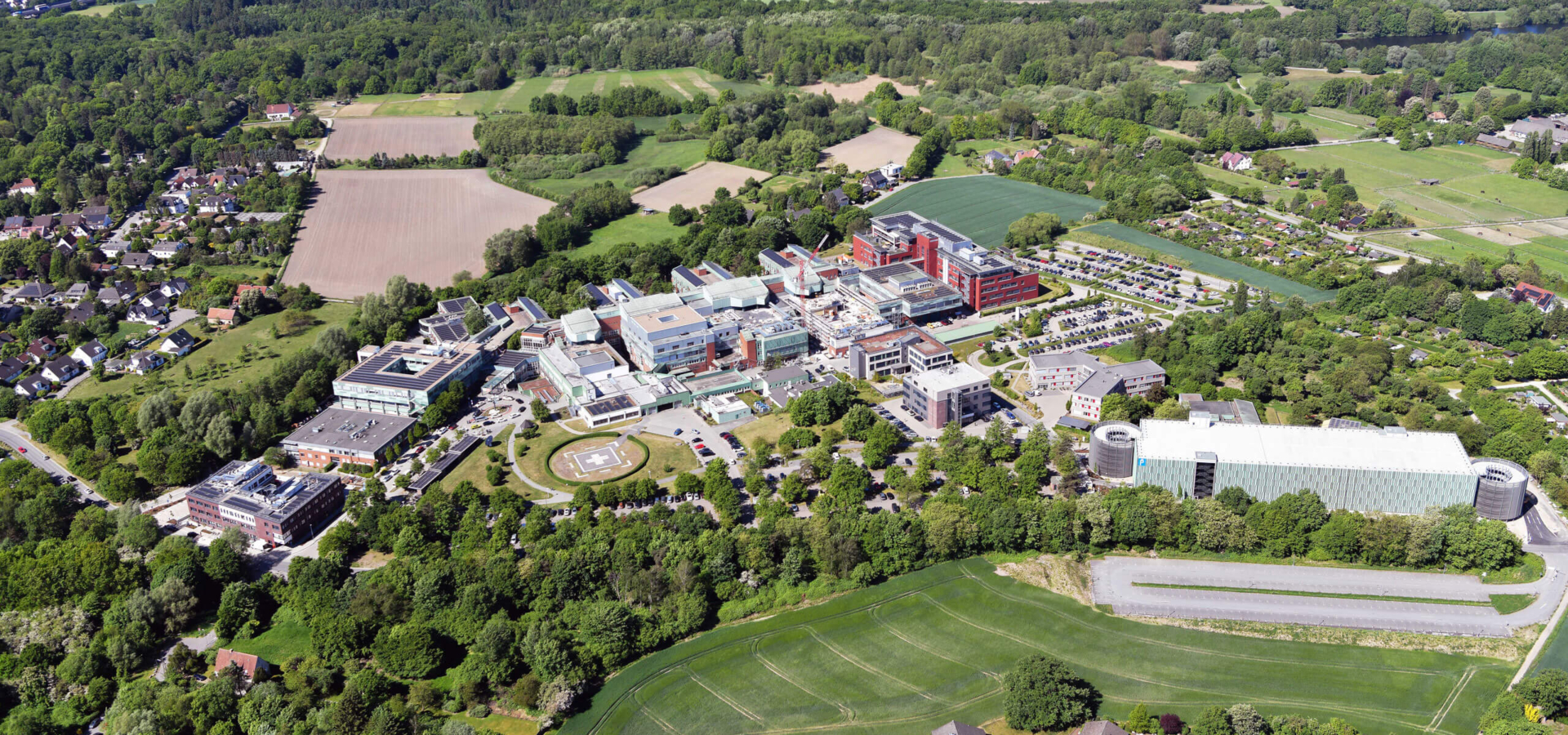 Vogelperspektive des weitläufigen Gebäudekomplexes des Klinikums Osnabrück, umgeben von Grünalgen, Feldern und Wohngebieten.