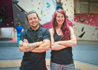 Ein Mann und eine Frau stehen mit verschränkten Armen lächelnd in einer Boulderdach-Halle.