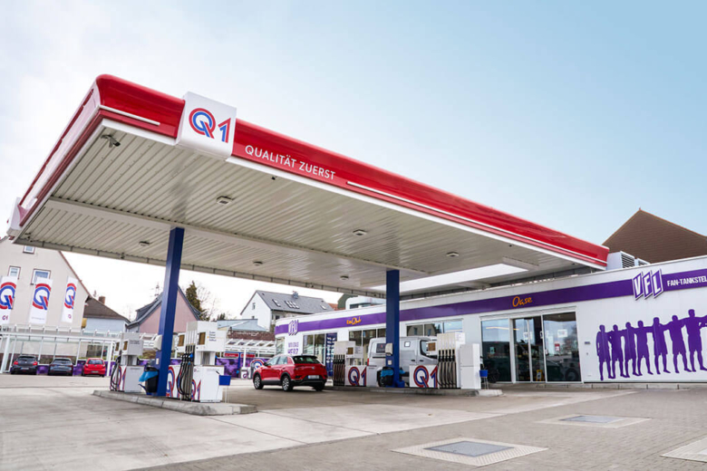 Modern überdachte Q1-Tankstelle mit Verkaufs-Shop und blau-roter Markenbeschriftung.