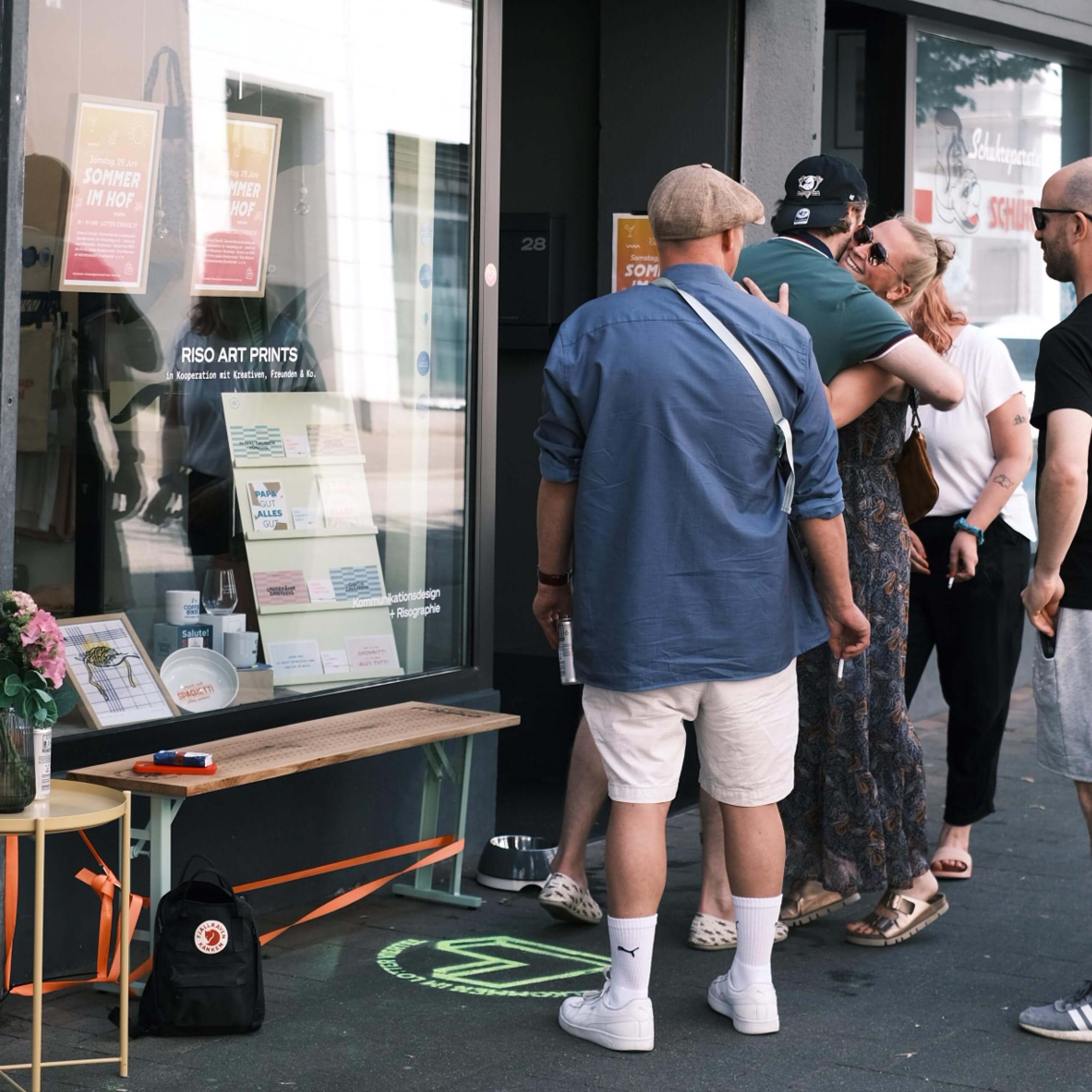 Mehrere Personen begrüßen sich herzlich vor dem Eingang eines Ladengeschäfts während eines Straßenfestes in der Altstadt.
