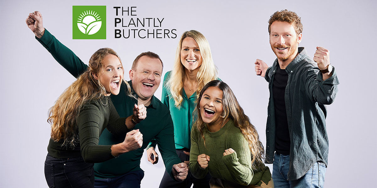 Fünf freudig jubelnde Personen posieren mit geballten Fäusten vor weißem Hintergrund unter dem Logo "The Plantly Butchers".