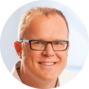Porträt von Thomas Gering mit Brille und lächelndem Gesicht in kreisförmigem Ausschnitt.