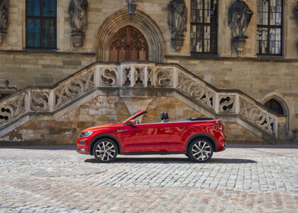 Rotes Volkswagen T-Roc Cabriolet steht auf Kopfsteinpflaster vor der historischen Fassade des historischen Rathauses Osnabrück.