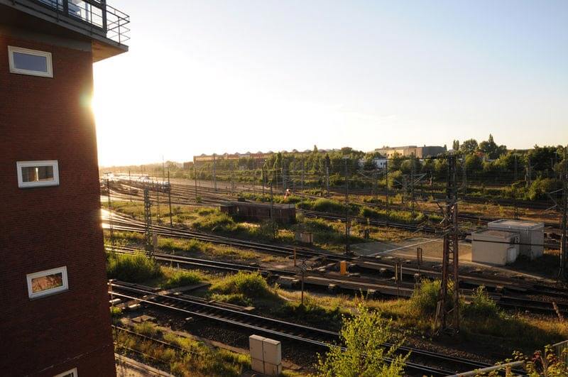 Blick auf ein weitläufiges Bahngelände mit vielen Gleisanlagen, Signalanlagen und Klinkergebäude im Abendlicht.
