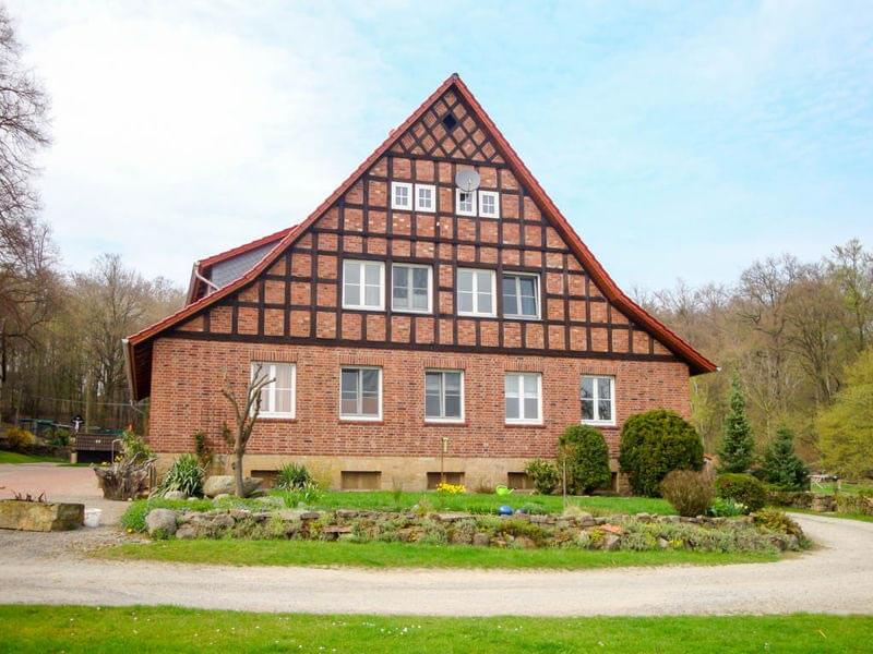 Großes, tradionelles Fachwerkhaus aus roten Backsteinen mit Kiesweg und gepflegtem Vorgarten im Vordergrund.