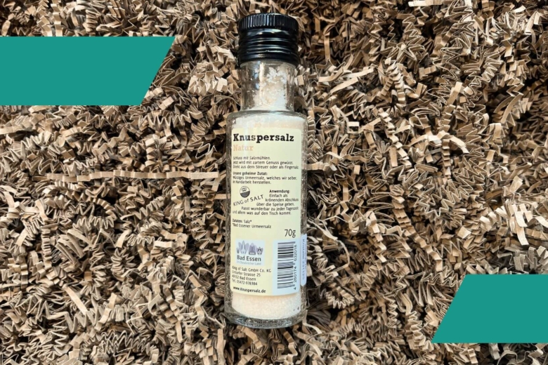 Schlanke Gewürzflasche von hinten mit Nährwert- und Herstellerangaben auf braunem Papierschnipselbett.
