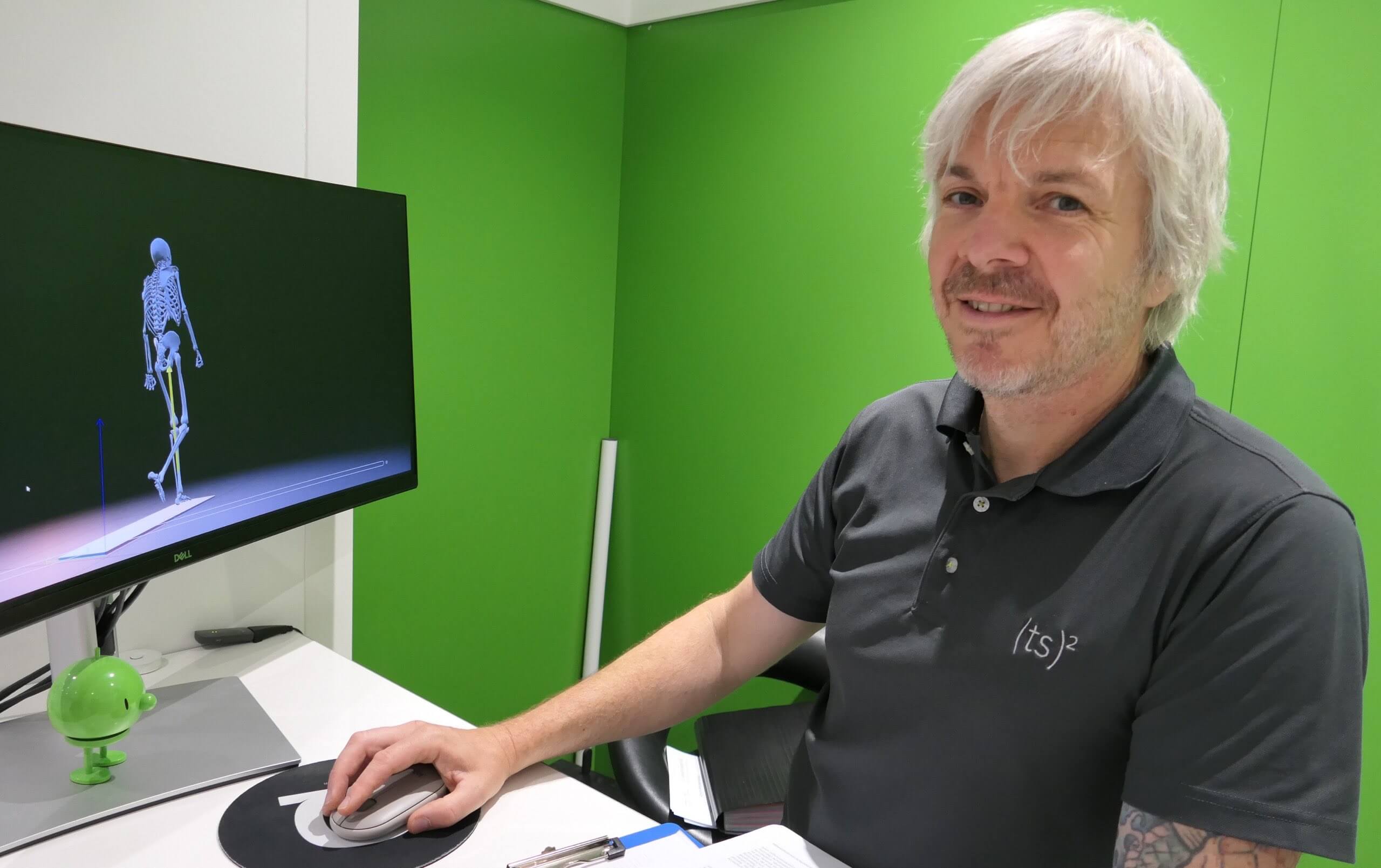Mann bedient eine PC-Maus vor einem Monitor mit der 3D-Analyse eines Skeletts beim Gehen.