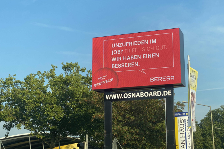 Großes rotes Werbedisplay an einer Hauptstraße mit der Aufschrift Unzufrieden im Job? Beresa hat einen besseren.