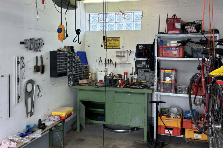 Eine aufgeräumte Werkstatt in einer Garage mit Werkzeugen an der Wand und aufgehängten Fahrrädern.
