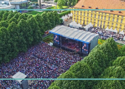Große Menschenmenge bei einem Open-Air-Konzert vor einer Hauptbühne im Schlossgarten Osnabrück, umgeben von Bäumen.