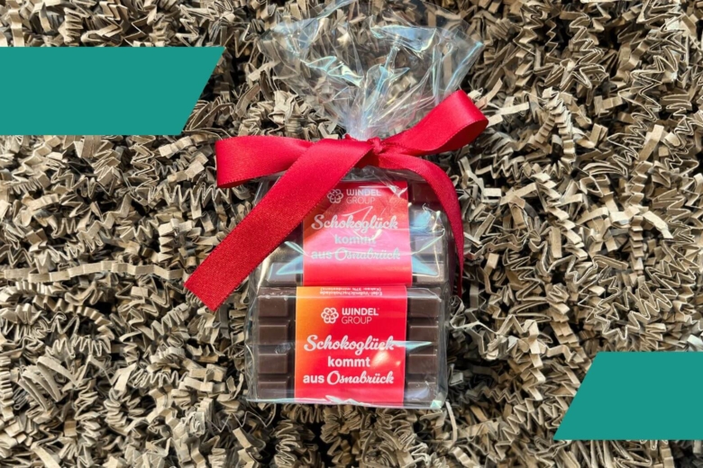 Kleine Schokoladentafeln in Folie verpackt mit roter Schleife und der Aufschrift „Schokoglück kommt aus Osnabrück“.