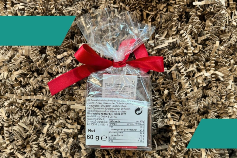 Verpackte Schokolade von hinten mit Nährwerttabelle und roter Schleife auf braunem Verpackungsmaterial.